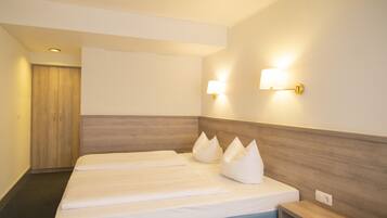 A hotel room with a large bed, two bedside tables, a nightstand, and two wall-mounted lamps.