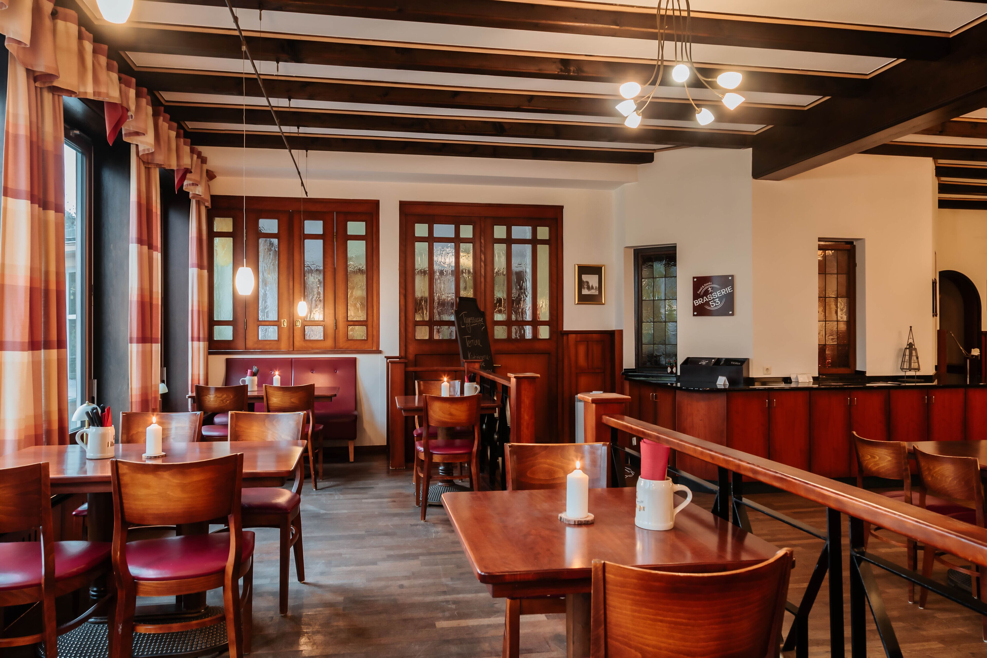 A restaurant with wooden furniture, candle-lit tables, and a bar area.