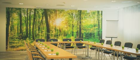 A conference room with a long table, chairs, and a projector screen.