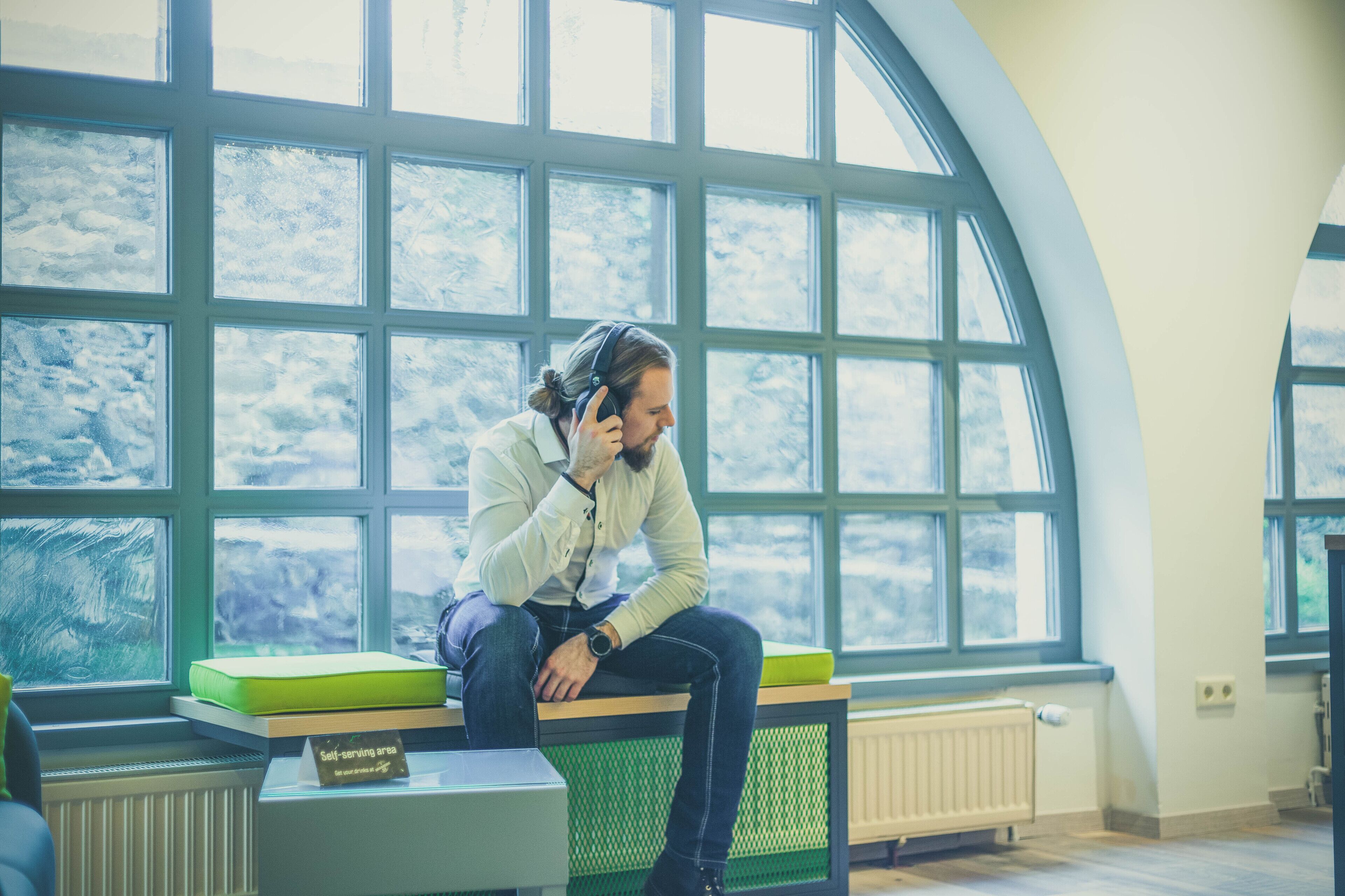 A person sitting on a bench in a room with large windows and a self-serve area.