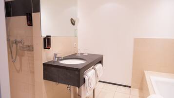 Un baño moderno con lavabo, espejo, toallero y ducha.