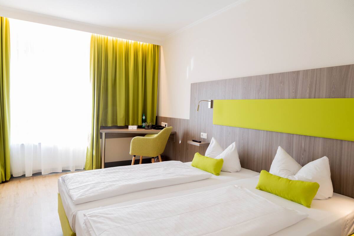 Une chambre d’hôtel avec deux lits, un bureau et une chaise.