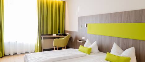A hotel room with two beds, a desk, and a chair.