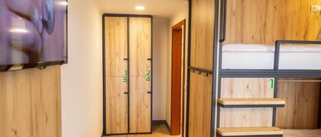A room with a bunk bed, wooden walls, a TV mounted on the wall, and a door with numbered sections.