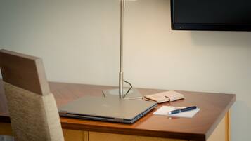 Un bureau en bois avec un ordinateur portable, une lampe, un carnet et un stylo.