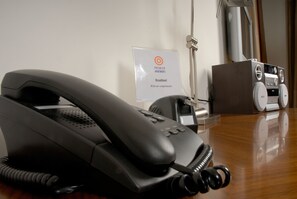 A black telephone on a wooden desk with a sign indicating broadband availability. - Premier Suites Dublin Sandyford (Dublin)