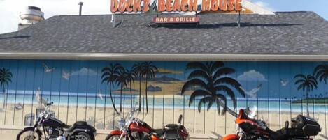 Dock's Beach House with a mural of a beach scene and three motorcycles parked in front.