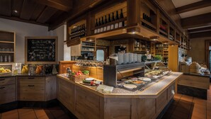 Un restaurant au décor intérieur en bois, un buffet proposant une variété de plats et des étagères remplies de bouteilles et de verres.