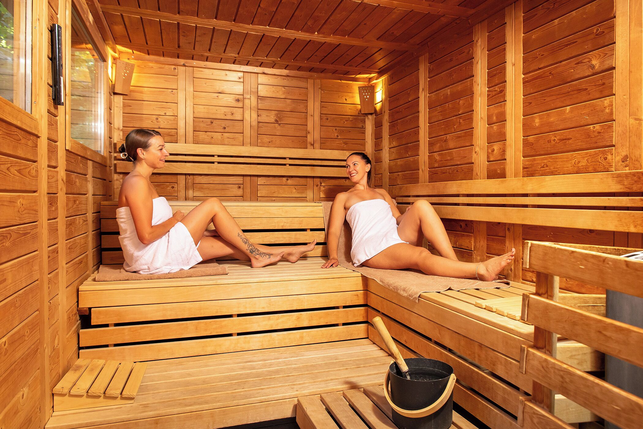 A sauna with wooden benches and a bucket.