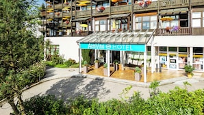 Un hôtel doté de nombreux balcons, d’un espace extérieur aménagé pour s’asseoir et de compositions florales.