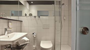 A modern bathroom with a glass-enclosed shower, a white sink, and a toilet.