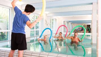 Swimmers enjoy the pool with clear glass walls and a textured ceiling.