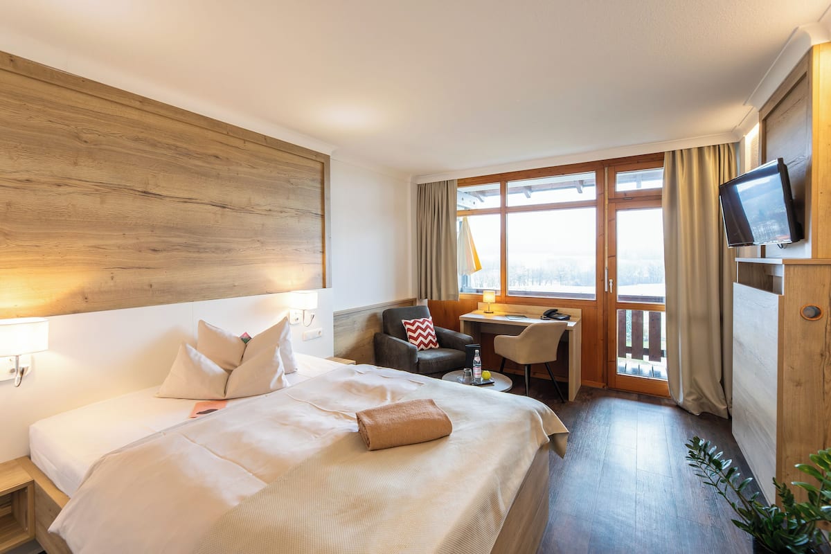 A hotel room with a bed, a desk, a chair, a television, and a window with curtains.