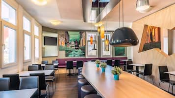 Een modern restaurantinterieur met hoge plafonds, grote ramen en een lange bar met krukken.