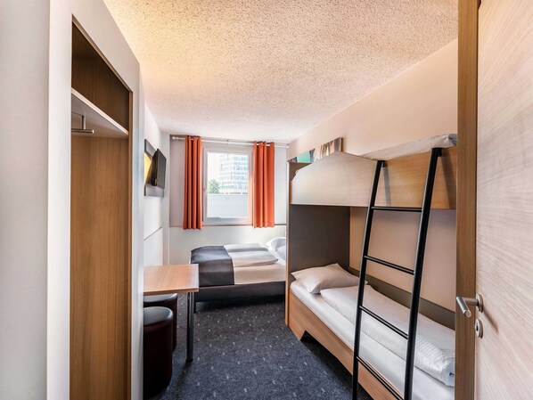 A compact hotel room with a bunk bed, a desk, and a wardrobe.
