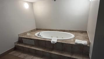 A modern bathroom with a freestanding bathtub, a towel rack, and a vent.
