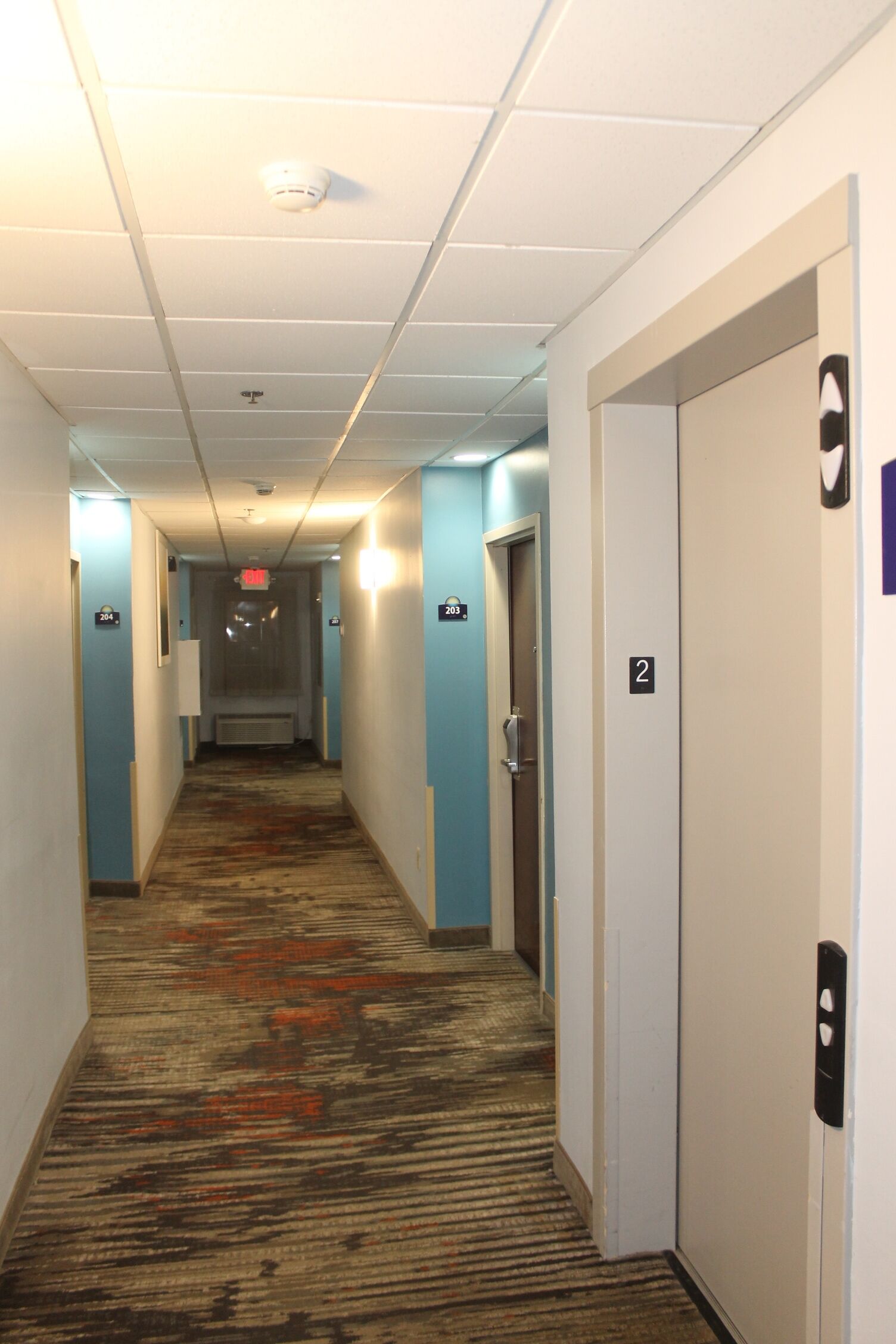 A hotel hallway with carpeted floors, white walls, and doors numbered 2, 3, and 4.