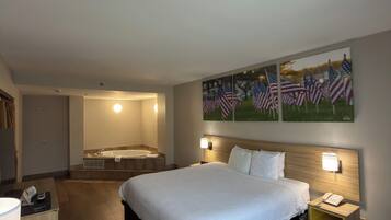 Une chambre d’hôtel avec un grand lit, une salle de bain avec une baignoire et un mur décoré de tableaux représentant le drapeau américain.