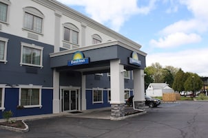 Um hotel Days Inn com fachada azul e branca, entrada coberta e estacionamento.