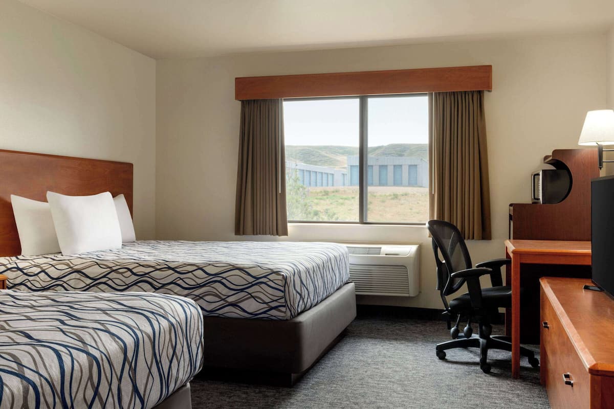 A hotel room with a large bed, a desk with a chair, and a television.