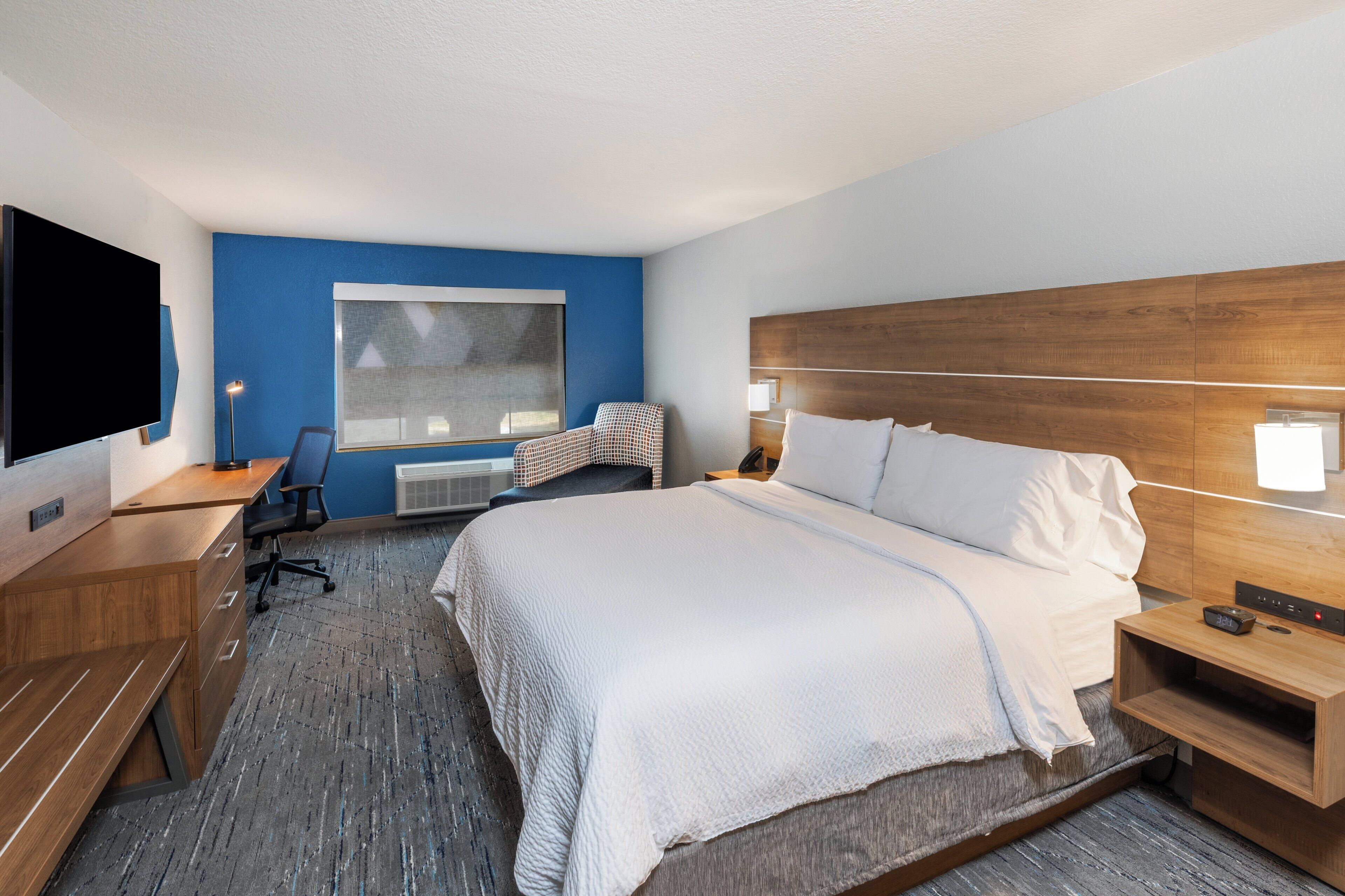 Een hotelkamer met een groot bed, een bureau met stoel, een flatscreen televisie en een raam.