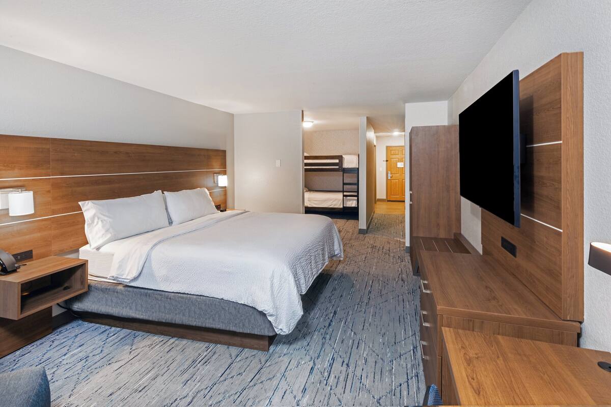 A hotel room with a large bed, bedside tables, a flat-screen TV, and a wooden wardrobe.