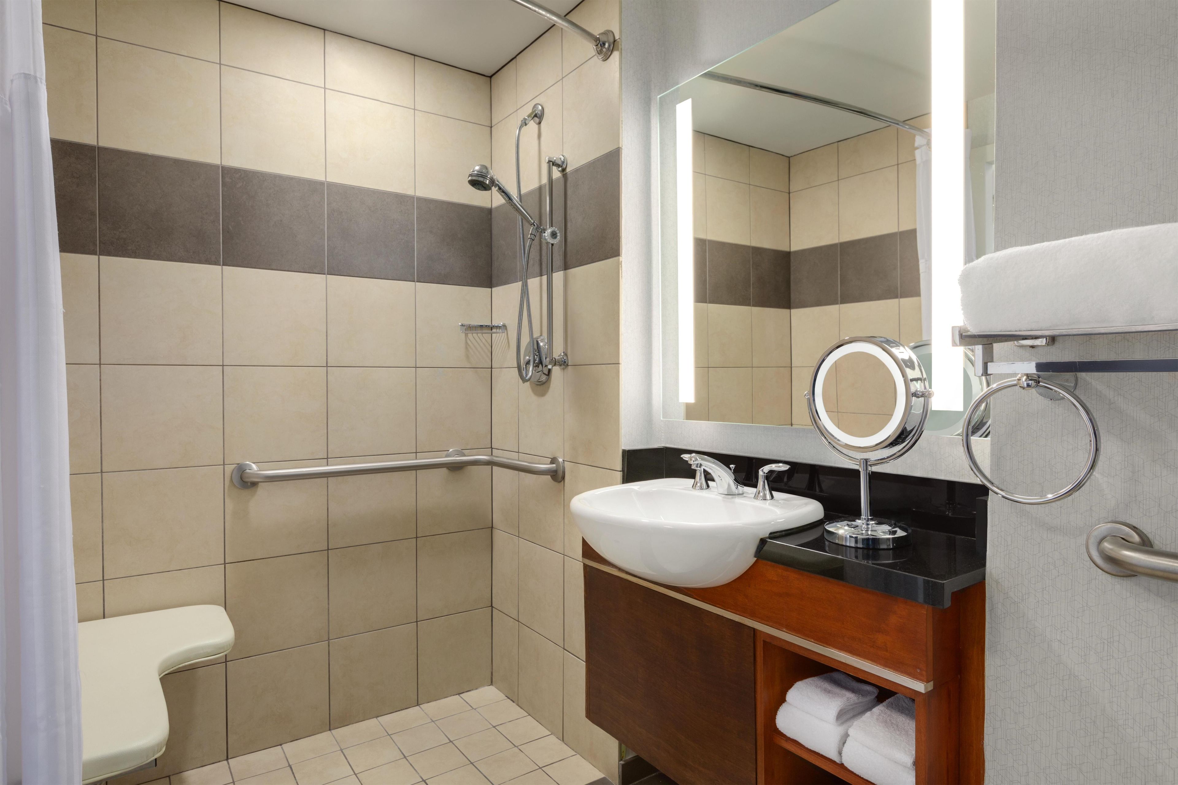 A bathroom with a shower, toilet, sink, and vanity.