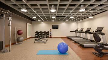 Un gimnasio con cintas de correr, pelotas de ejercicio y máquinas de pesas.
