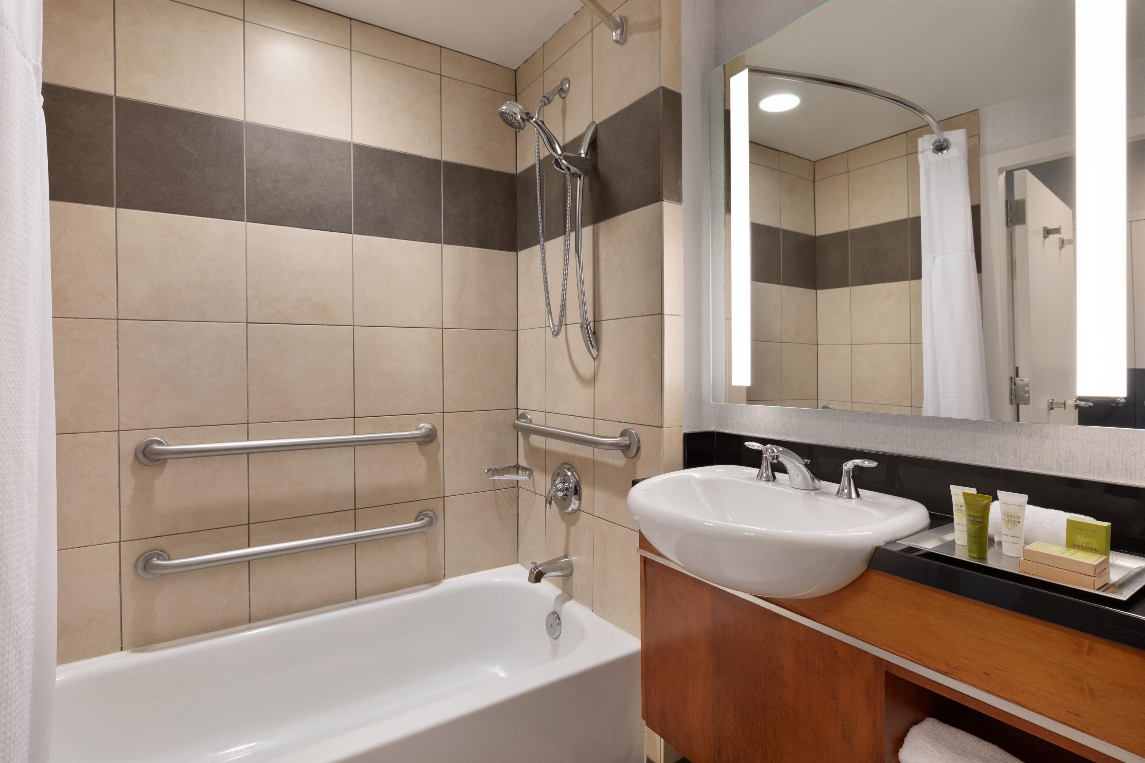 A modern bathroom with a bathtub, two sinks, a shower, and a mirror.