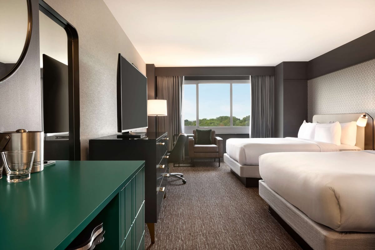 A hotel room with a large bed, a desk with a computer, a chair, and a view of the outdoors.