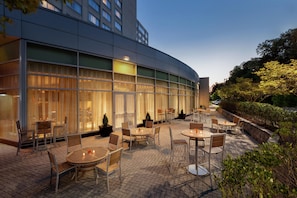 A hotel patio with outdoor seating, large windows, and a modern building facade. - Hilton Baltimore BWI Airport (Linthicum Heights)