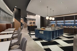 A modern restaurant with a central bar area, seating along the walls, and a checkered floor pattern. - Hilton Baltimore BWI Airport (Linthicum Heights)