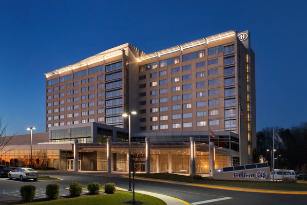 A multi-story hotel with a modern design, featuring a prominent entrance with a covered walkway and a large sign displaying the brand name. - Hilton Baltimore BWI Airport (Linthicum Heights)