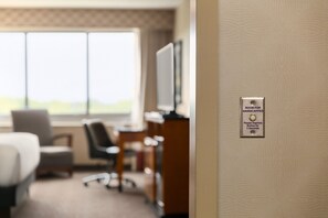 A hotel room with a bed, a desk, a chair, and a television. There is a sign on the wall indicating a room for handicapped individuals. - Hilton Baltimore BWI Airport (Linthicum Heights)
