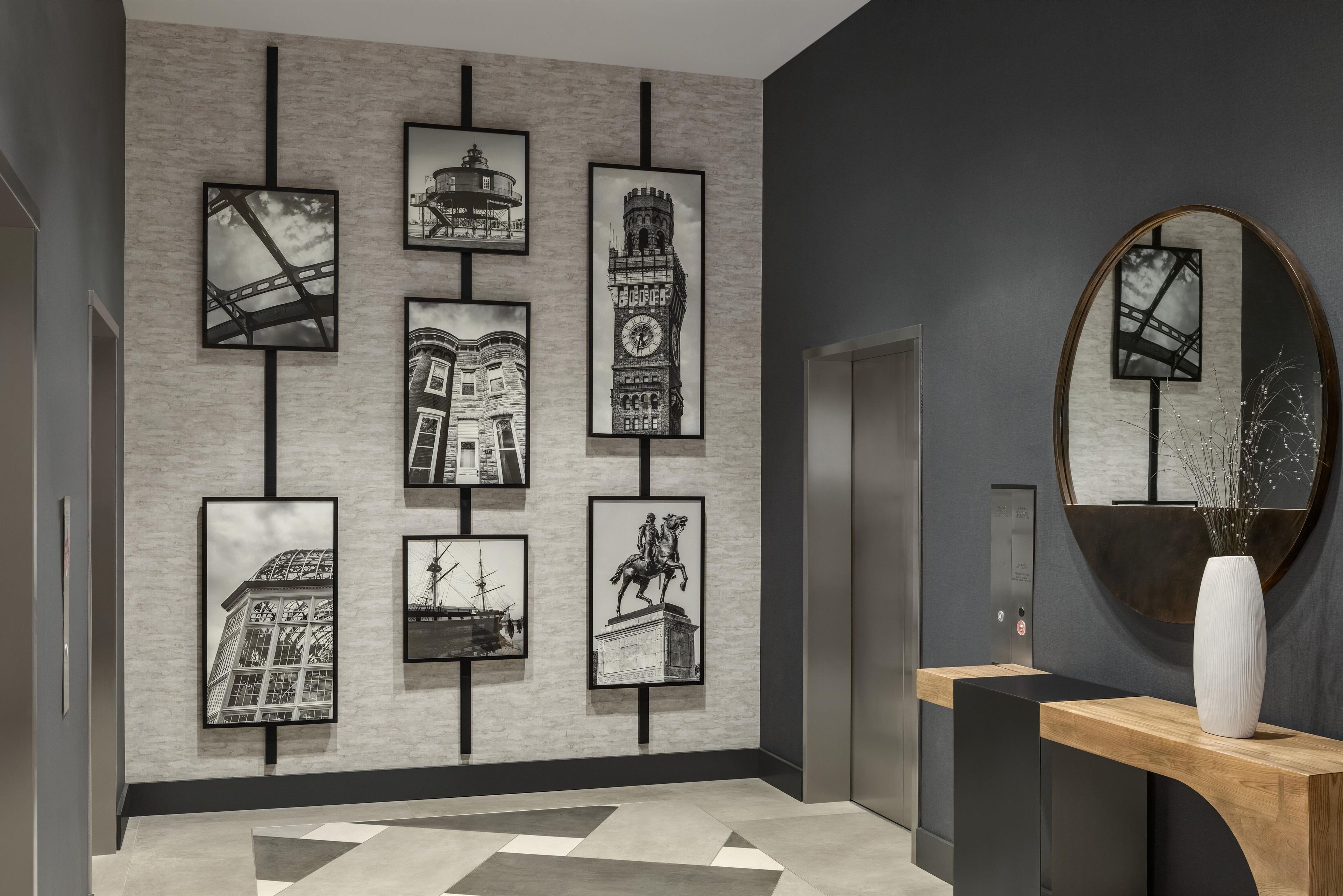 A modern reception area with a geometric patterned floor, a reception desk, and a series of framed black and white photographs on the wall.