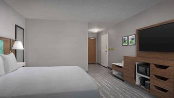 A hotel room with a large bed, a TV, a microwave, and a small kitchenette.