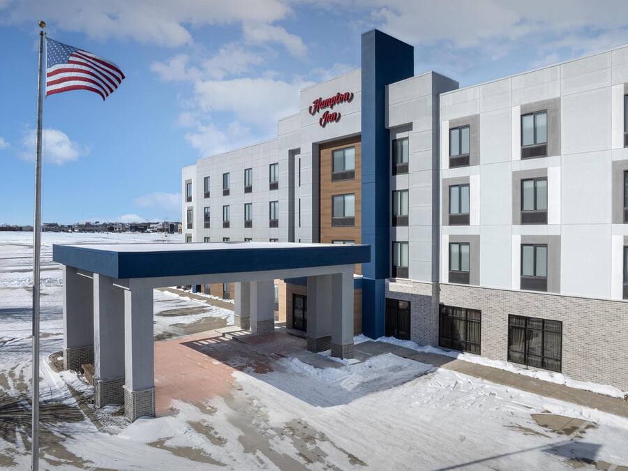 Un hotel moderno con una vistosa bandiera americana, caratterizzato da un design pulito e contemporaneo, con facciata in mattoni e vetro.