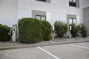 A parking area with electric vehicle charging stations and a building with a modern design.
