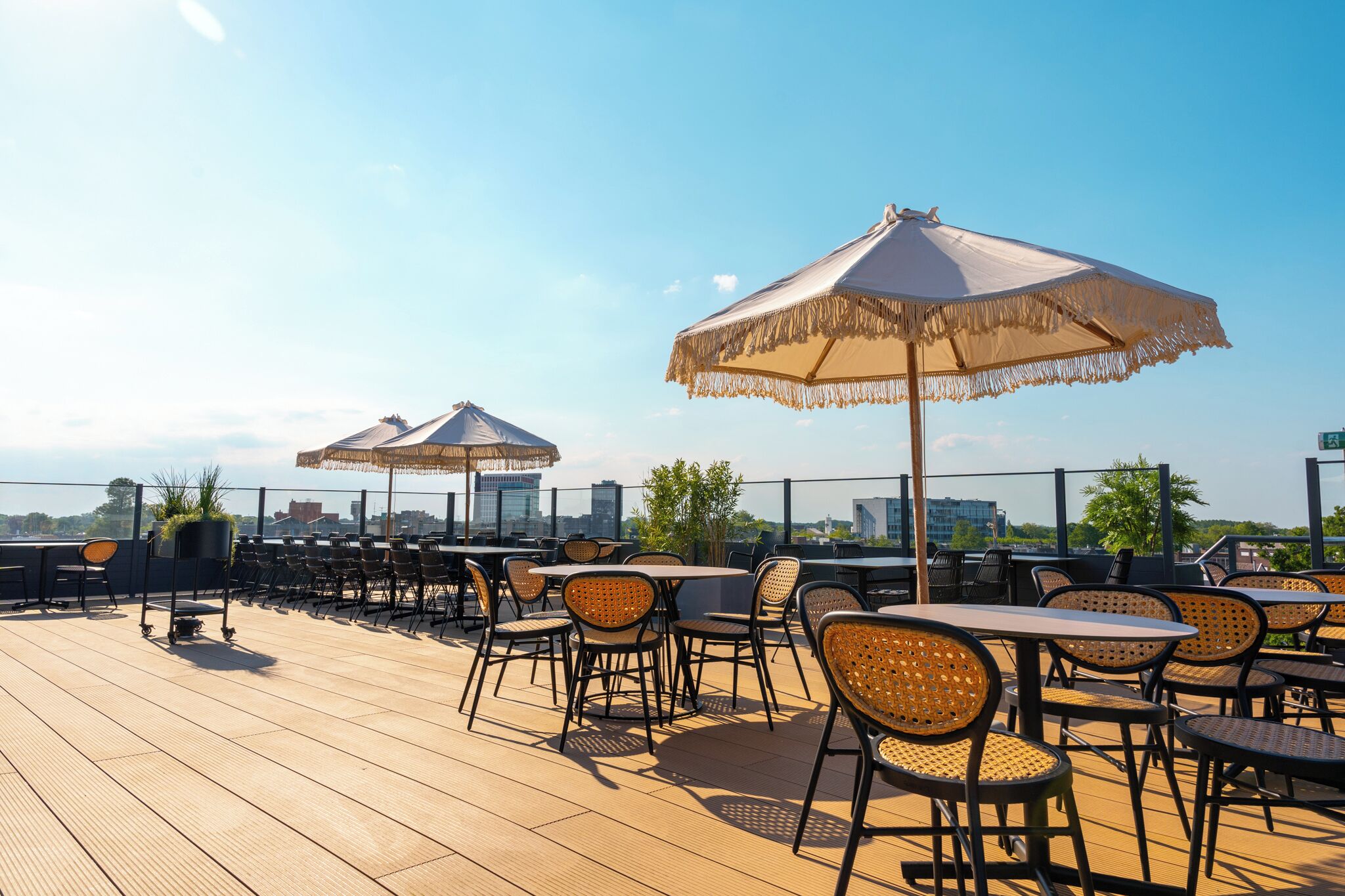 An outdoor seating area with tables and chairs, umbrellas, and a view of the city skyline.