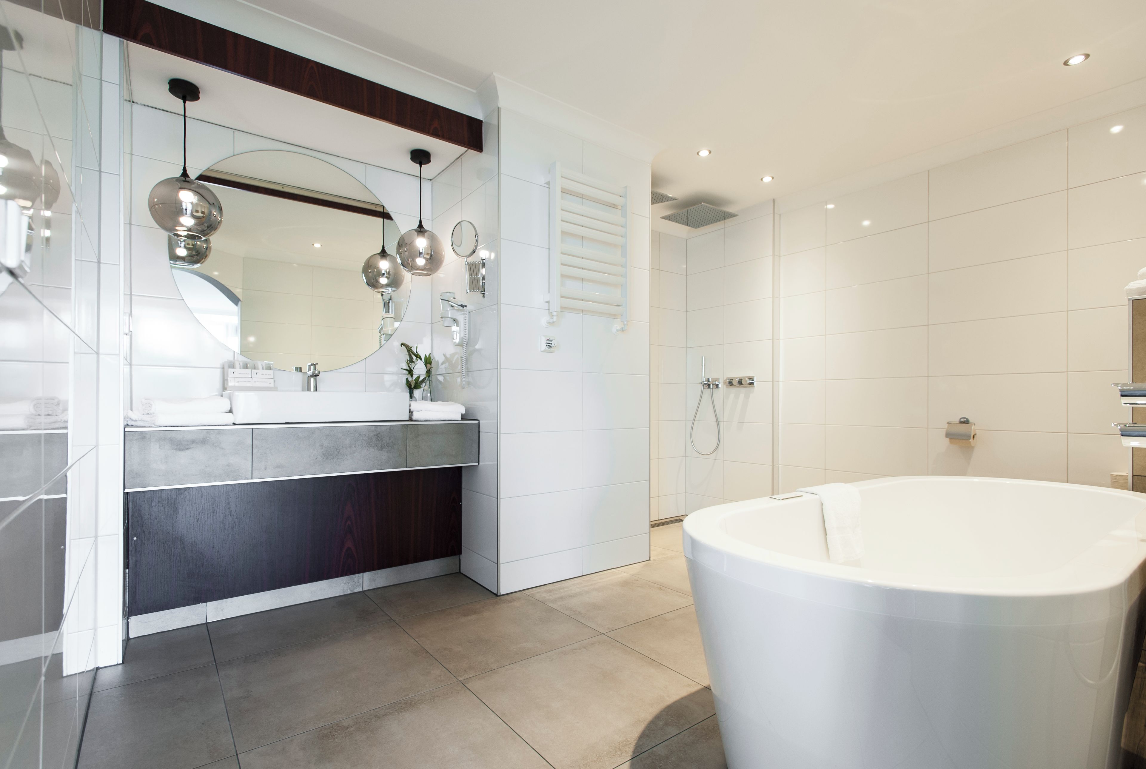 Un baño moderno con una bañera independiente, un tocador con espejo y una zona de ducha.