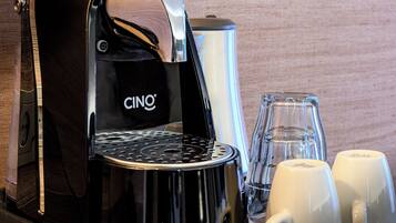 A CINO coffee maker with two white cups and two clear glasses on a table.