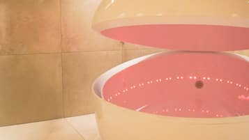 Une grande structure circulaire blanche, avec un intérieur rose, qui pourrait être un élément décoratif aquatique, dans une pièce carrelée éclairée par des luminaires au plafond.
