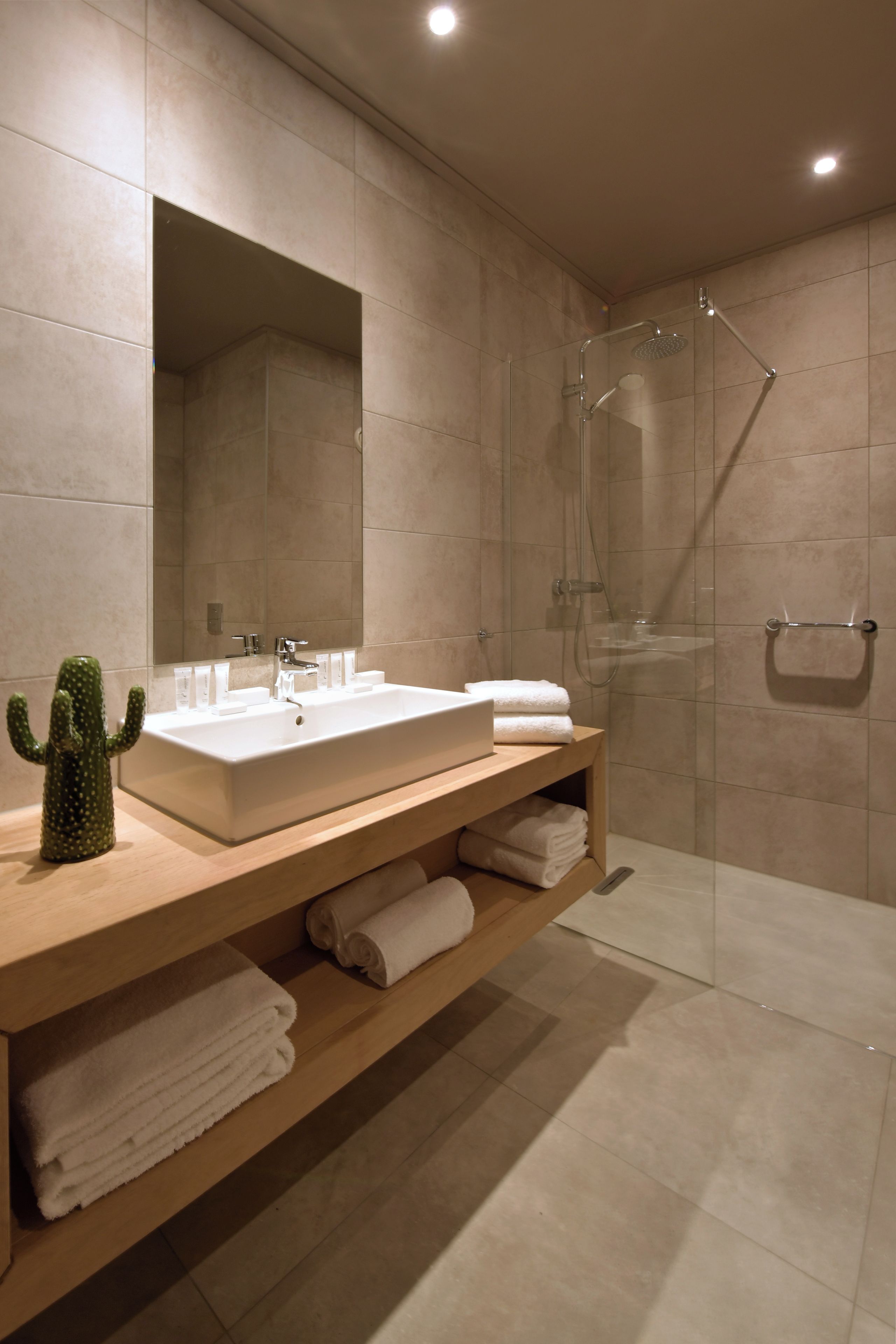 Un baño moderno con un espejo grande, un lavamanos y una ducha.