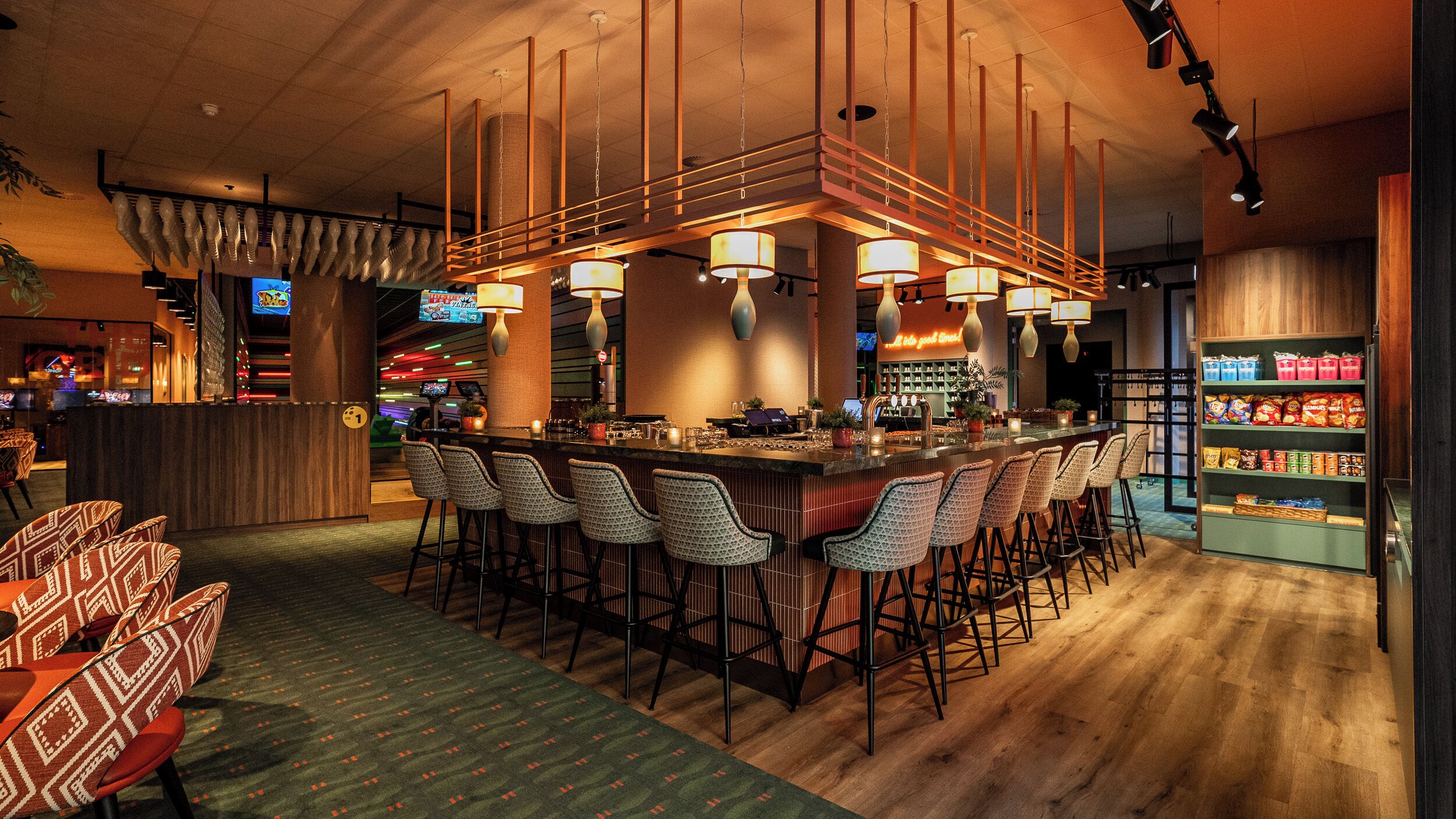 A bar area with multiple seating options, including bar stools and chairs, and a counter with a variety of snacks and beverages.