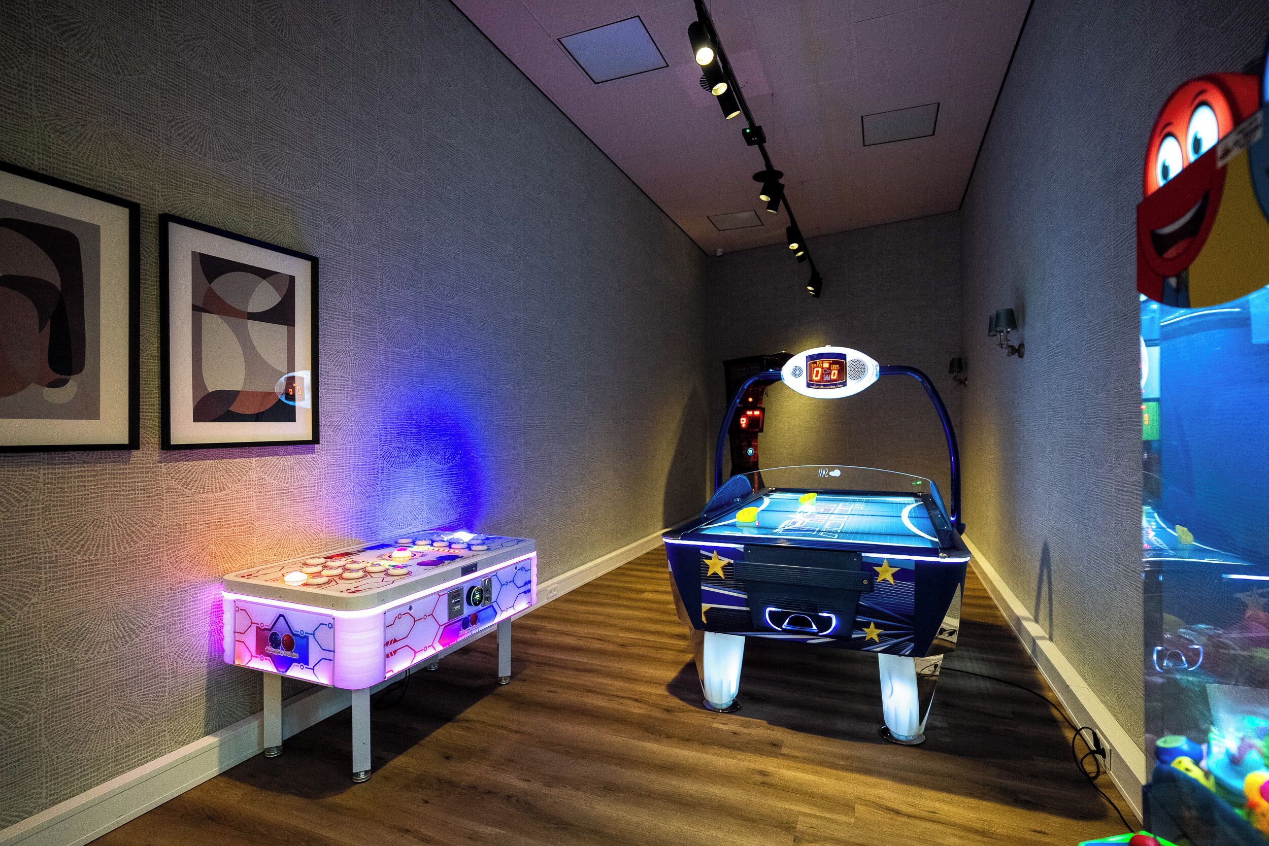 Una habitación con mesa de fútbol de mesa, marcador digital y juegos de arcade.