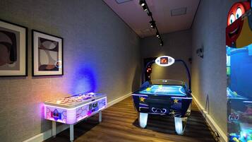 Una habitación con mesa de fútbol de mesa, marcador digital y juegos de arcade.