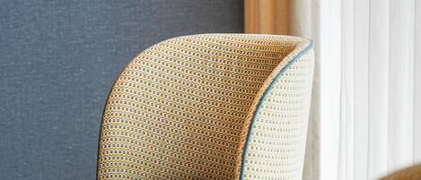 Une chaise dotée d’un dossier en osier et d’un coussin, placée à côté d’une table en bois sur laquelle se trouve un magazine.