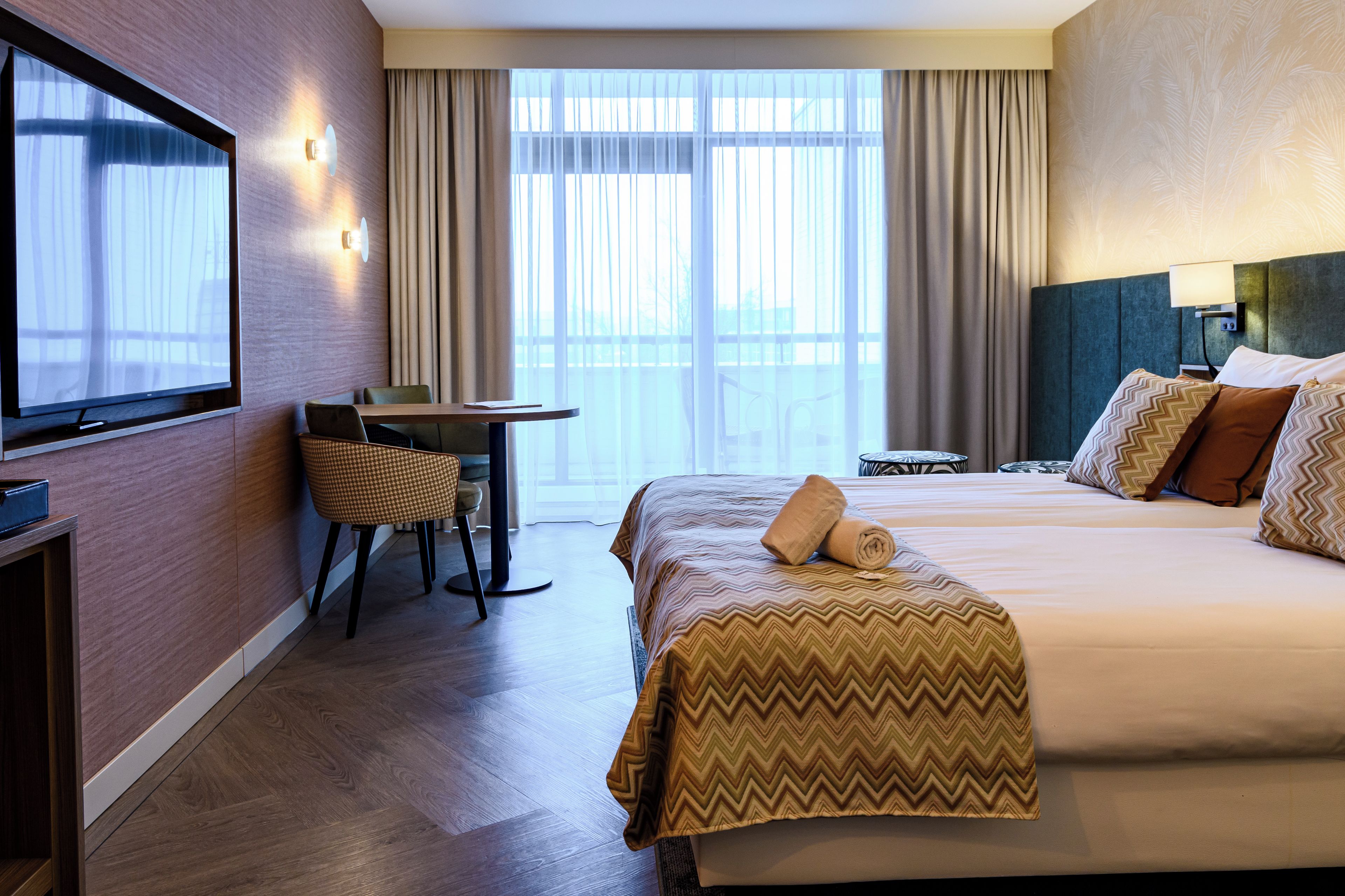 Una habitación de hotel con una cama, un escritorio, una silla y un televisor.
