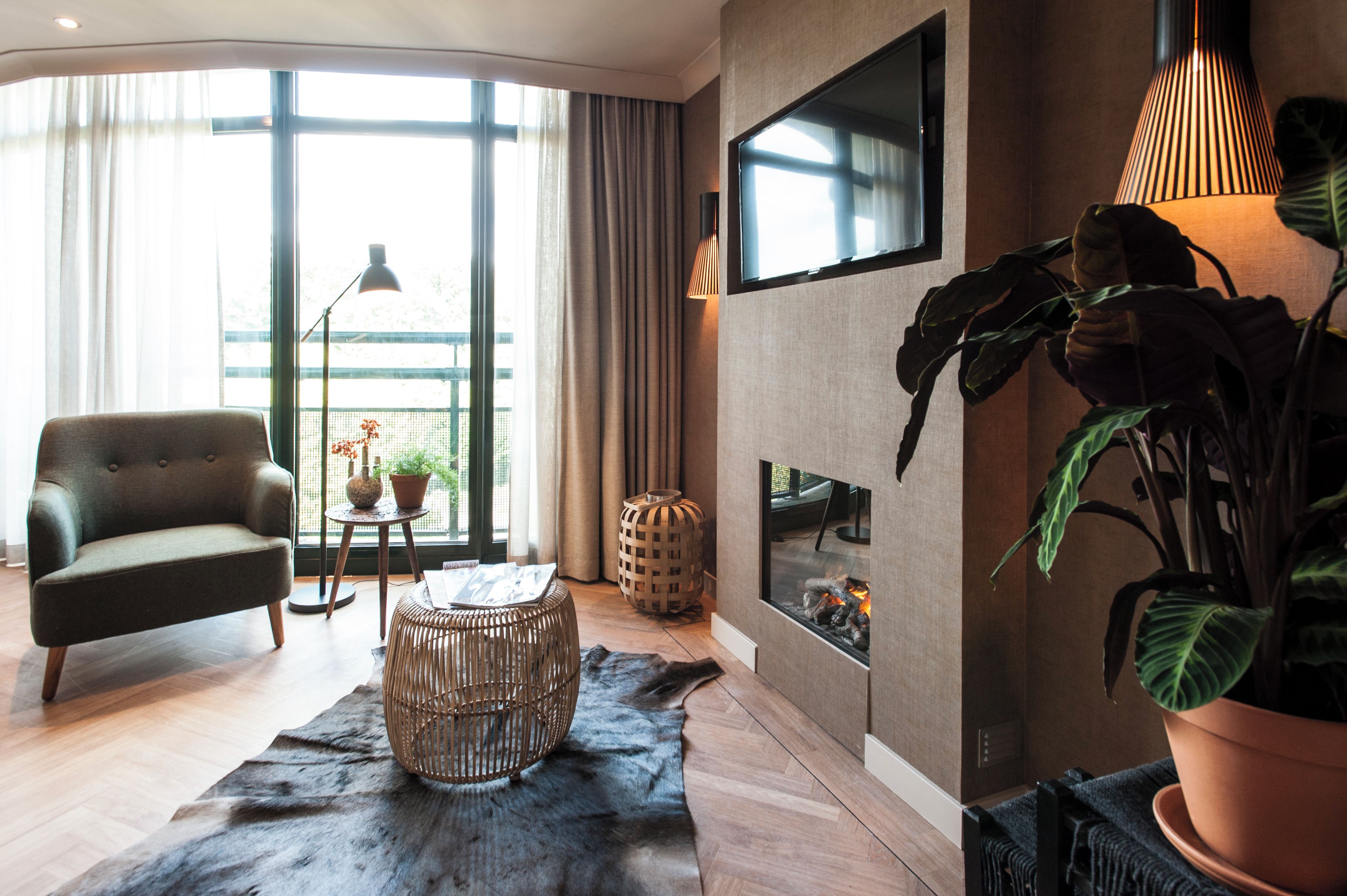 Ein modernes Wohnzimmer mit einer Couch, einem runden Tisch, einem Kamin und einem großen Fenster.