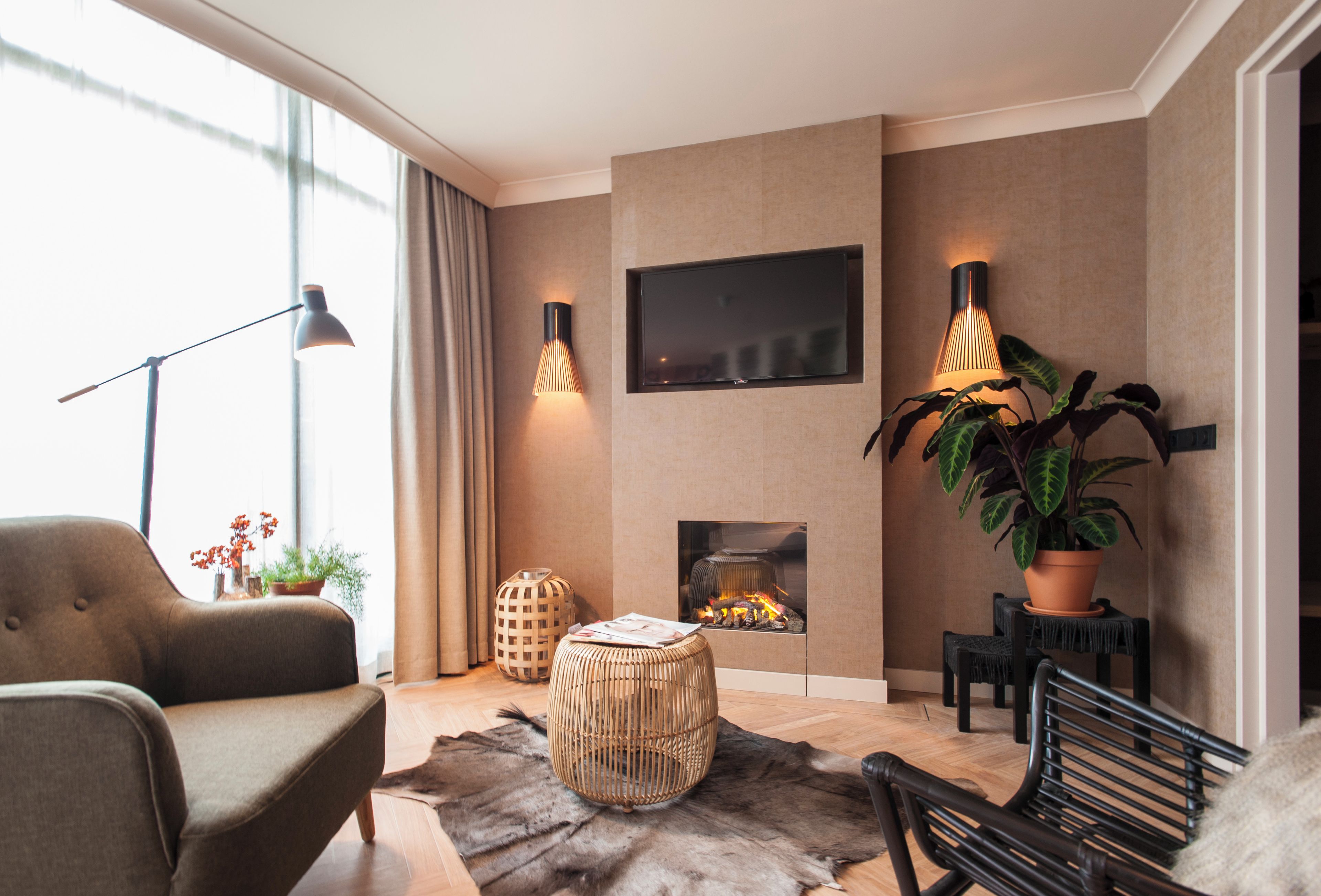 A modern living room with a sofa, a coffee table, a fireplace, and a television mounted on the wall.